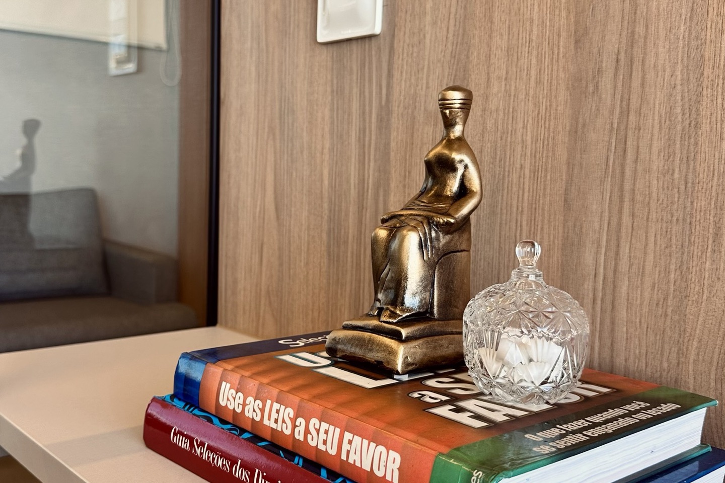 Escultura da Justiça sobre livros na estante do escritório