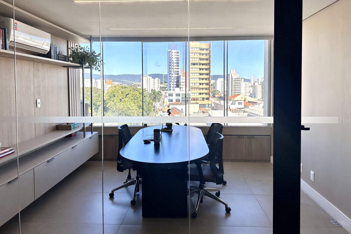 Sala de reunião com mesa oval e vista panorâmica do centro de Jundiaí